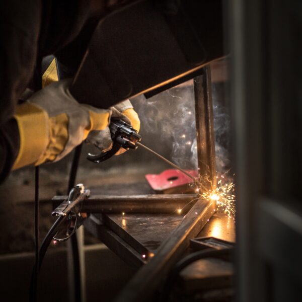 a man with a welding machine welds a metal structure, sparks fly.