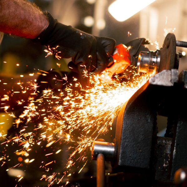 close-up of car mechanic working at a service station with an angle grinder from which sparks fly